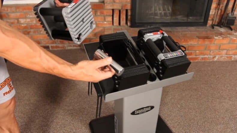 man cganging adjustable weight pins inside powerblock dumbbell