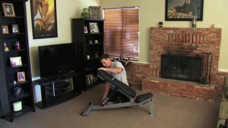 man adjusting powerblock sports bench in front room of house