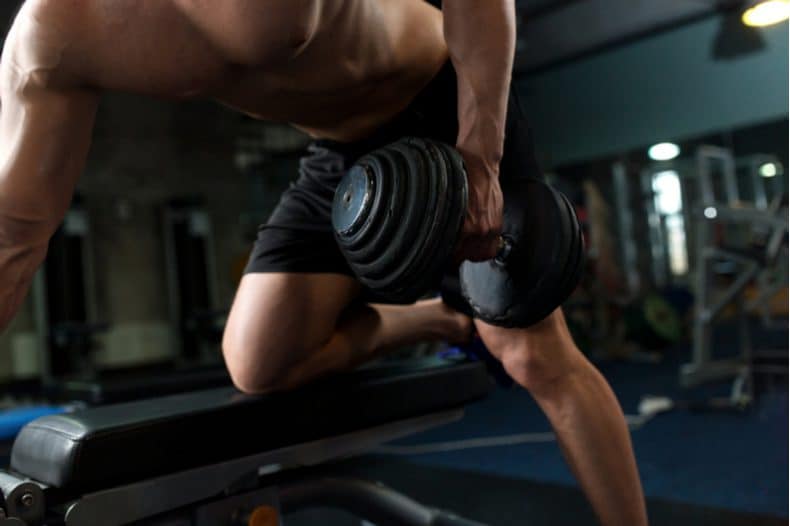bodybuilder performing one arm rows
