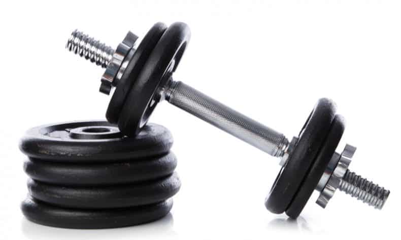 spin lock adjustable dumbbell resting on weight plates on white back ground