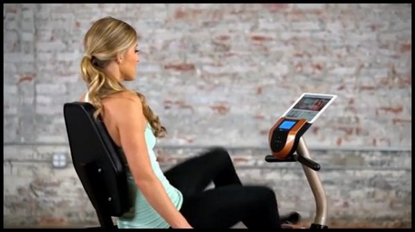 woman viewing her ipad while exercising on Exerpeutic gold 975xbt recumbent bike