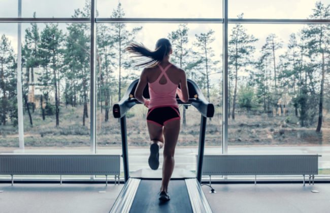 fit woman running on a treadmill in front of the window
