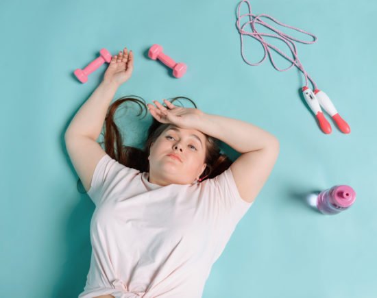 chubby woman laying exhausted after doing fat burning workouts