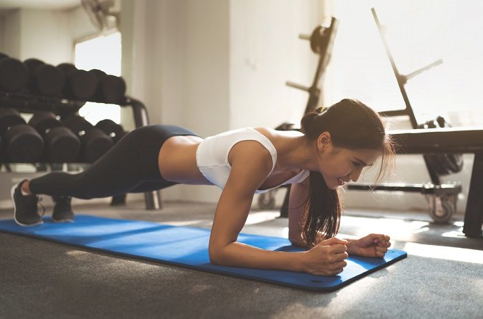 woman performing planks exercise in her local gym