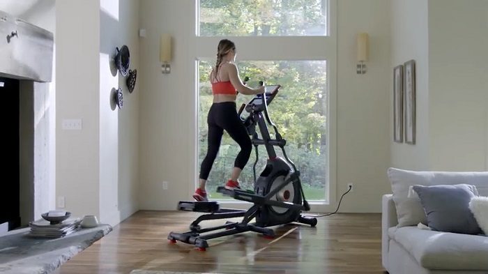 woman exercising on Schwinn elliptical in front of a window in her home