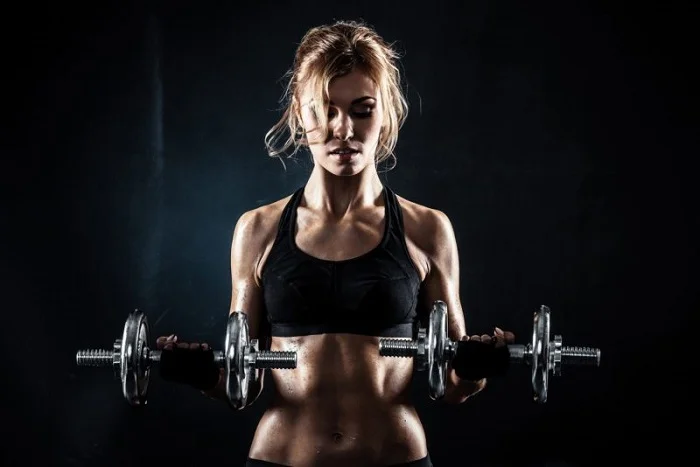 fit blond woman holding weights showing 6 pack abs