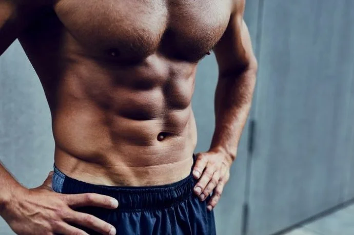 fit man wearing a blue shorts showing 6 pack abs
