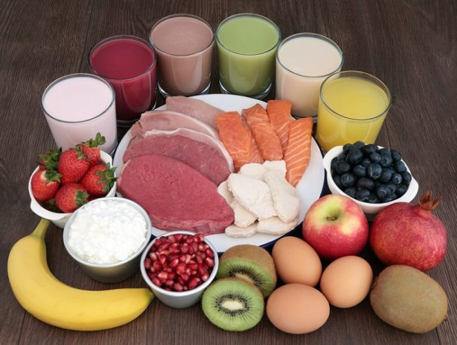 variety of food plate of meat surrounded by protein shakes and various fruit and eggs