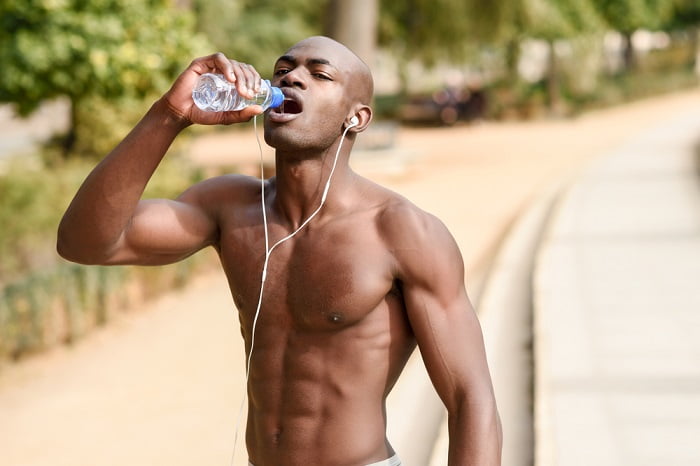 young fit man drinking water fit black man drinking water from a bottle