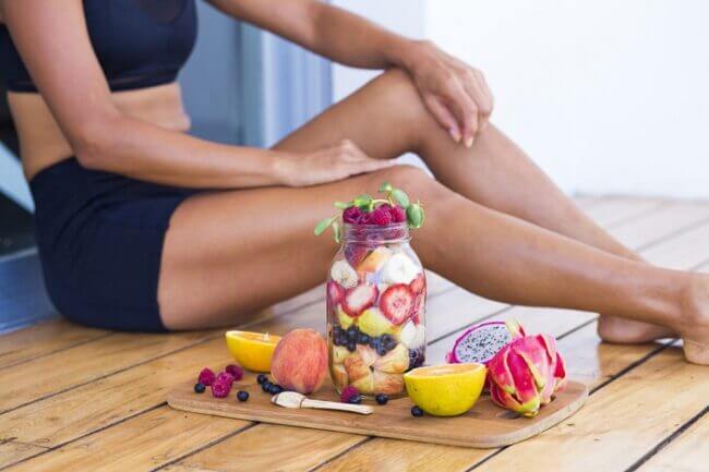 image representing healthy diet and fitness a young woman sitting next to the jar with fruit