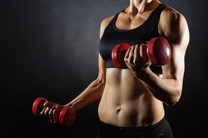 sets and reps fit woman holding red dumbbells doing sets and reps
