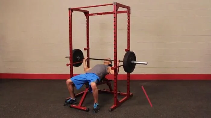 man performing bench press on best fitness power rack