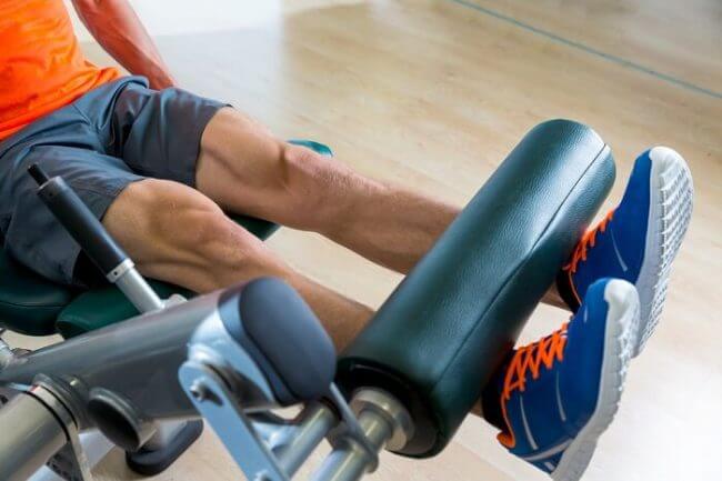 leg extension fit man doing leg extension exercise on a machine