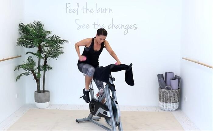 Spinning Indoor Cycling workout woman with dumbbell on spinning bike