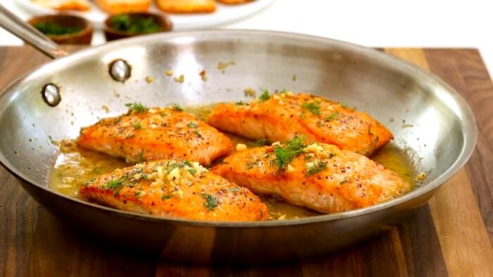 4 cooked salmon fillets in a frying pan