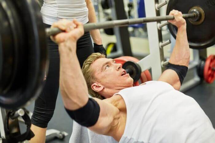 man being spotted by girlfriend incline pressing