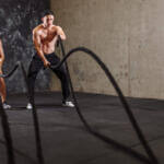 man and woman performing battle rope workout