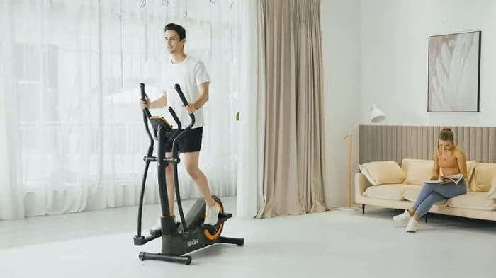 NICEDAY Elliptical Machine in home gym Man pedaling niceday elliptical in the front room of his house