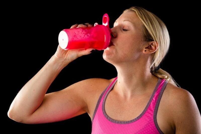woman drinking pre-workout from mixer