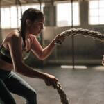woman being taught how to use battle rope in the gym