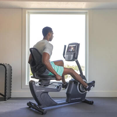 man pedaling on his proform recumbent bike in his home gym