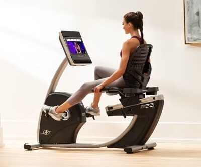 woman pedaling on nordictrack recumbent bike in her home gym