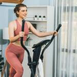 woman pedalling elliptical pink gym outfit at home