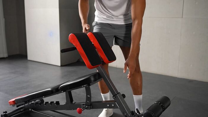 man adjusting preacher curl attachment of finer form FID bench